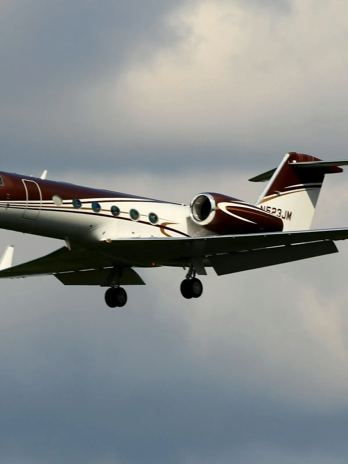 Business jet with a red tail in flight under a grey sky